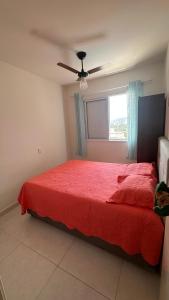 - une chambre avec un lit rouge et un ventilateur de plafond dans l'établissement Lindo apto com vista para o mar, à Guarujá 30 autres photos