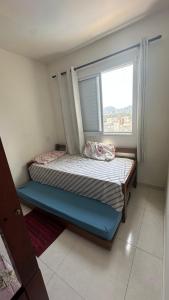 un petit lit dans une chambre avec une fenêtre dans l'établissement Lindo apto com vista para o mar, à Guarujá