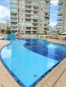 une grande piscine d'eau bleue en face d'un bâtiment dans l'établissement Lindo apto com vista para o mar, à Guarujá