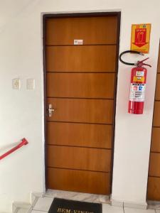 a fire extinguisher hangs above a wooden door at Apartamento Solaris in São Luís