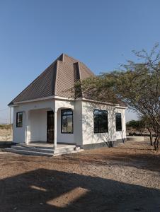 a small white building with a gambrel roof at Nyumbani House in Mto wa Mbu