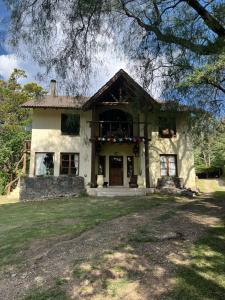 ein weißes Haus mit einem Baum davor in der Unterkunft Posada La Lucía in Villa General Belgrano
