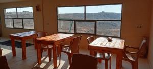 two tables and chairs in a room with windows at Alnwatif Gate guest house Dana nature reserve in Dana
