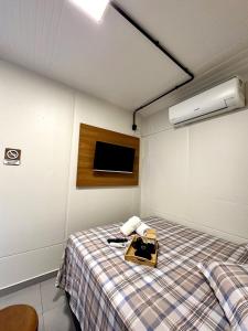 弗洛里亚诺波利斯Loft 1 A poucos minutos do aeroporto e praias的房间里有一张床和一台挂在墙上的电视