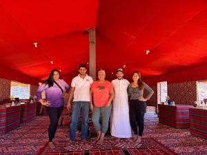 un groupe de personnes debout sous une tente rouge dans l'établissement Star Walk Camp & Tours, à Wadi Rum