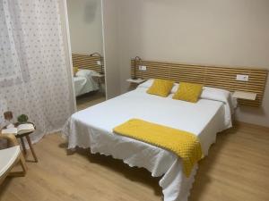 a bedroom with a large white bed with yellow pillows at Villa Lila - planta 1ª in Pontevedra