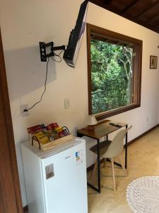 Il comprend une cuisine équipée d'un réfrigérateur et d'une table avec une fenêtre. dans l'établissement Pousada ViniCarmel Arraial d ajuda, à Arraial d'Ajuda