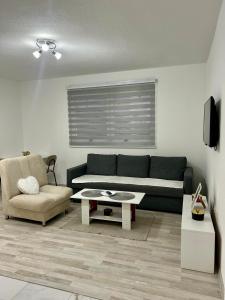 una sala de estar con un sofá y una silla en Apartman M, 