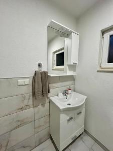 Un baño blanco con lavabo y espejo. en Apartman M, 