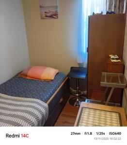 a small bedroom with a bed and a stool at Alojamiento Monitor Huáscar in Talcahuano