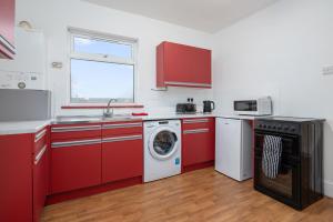 a kitchen with red cabinets and a washing machine at Immingham Contractors stay in Immingham