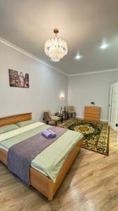 ein Schlafzimmer mit einem großen Bett und einem Kronleuchter in der Unterkunft Квартира на левом берегу в ЖК Alpamys A4 in Astana