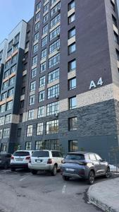ein großes Gebäude mit auf einem Parkplatz abgestellten Autos in der Unterkunft Квартира на левом берегу в ЖК Alpamys A4 in Astana