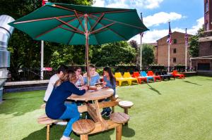 a group of people sitting at a table under an umbrella at Rest Up London in London