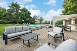a deck with a couch and chairs next to a pool at L'Écrin des Greens in Dommartin