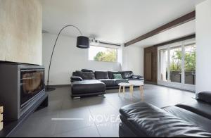 a living room with black leather furniture and a fireplace at L'Écrin des Greens in Dommartin