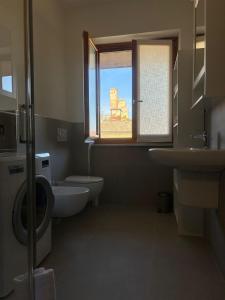 a bathroom with a toilet and a sink and a window at Appartamento Le Aie in Serralunga d'Alba