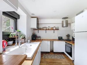 Una cocina con gabinetes blancos y un refrigerador blanco. en Le Moulin Hochet, en Les Pieux 18 fotos más