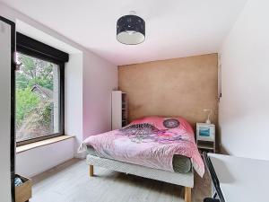 a bedroom with a pink bed and a window at Le Moulin Hochet in Les Pieux