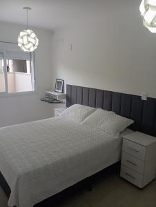 a bedroom with a bed and a chandelier at Apartamento com piscina, terraço, churrasqueira e estacionamento in Pelotas