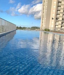 a pool of water in front of a building at Apartamento com piscina, terraço, churrasqueira e estacionamento in Pelotas