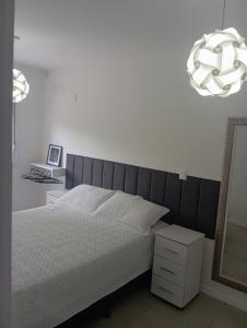 a bedroom with a white bed and a mirror at Apartamento com piscina, terraço, churrasqueira e estacionamento in Pelotas +18 photos