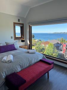 a bedroom with a large window with a view of the ocean at Lujosa casa en Playa Hermosa vista lago y volcanes in Puerto Varas