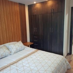 - une chambre avec un lit et des placards en bois dans l'établissement Comfortable departamento de 2 habitacones en la Victoria con garaje gratis, à Ibarra