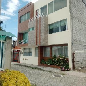 un immeuble avec une porte rouge dans l'établissement Comfortable departamento de 2 habitacones en la Victoria con garaje gratis, à Ibarra