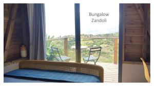 a bed in a room with a view of a balcony at VillAnolis in Le Carbet