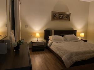 a bedroom with a large bed with two lamps on it at Modern apartment with garden in Sheikh Zayed