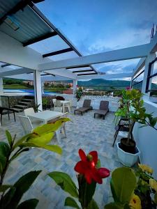 un patio avec des tables et des chaises blanches et une fleur rouge dans l'établissement Hotel Wiky House, antes la casona de Wiky, à Guaduas