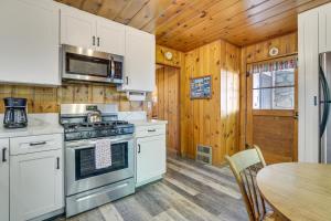 eine Küche mit weißen Schränken, einem Herd und einem Tisch in der Unterkunft Private Dock on Lake Arrowhead! Cozy Mtn Cabin in Lake Arrowhead
