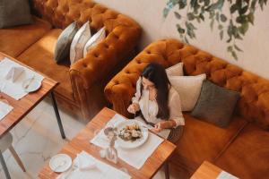 een vrouw die aan een tafel zit met een bord eten bij The Log Porto Hotel by Piamonte Hotels in Porto