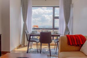 a dining room with a table and chairs and a large window at Duplex 1BR Apartment along Waiyaki Way, Nairobi in Nairobi