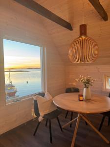 Rorbu med fantastisk utsikt i Brønnøysund في Salhus: غرفة طعام مع طاولة ونافذة كبيرة