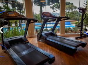 a gym with two exercise bikes and a swimming pool at Apartment no Wish Serrano 53 in Gramado