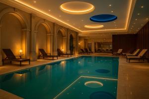 a swimming pool in a hotel with chairs and a ceiling at Greif Hotel & Spa in Trieste
