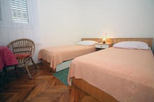 ein Schlafzimmer mit zwei Betten, einem Stuhl und einem Fenster in der Unterkunft Apartman Mravinac in Tisno