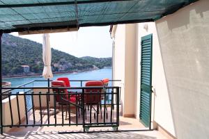 ein Balkon mit Stühlen und Blick aufs Wasser in der Unterkunft Apartman Mravinac in Tisno