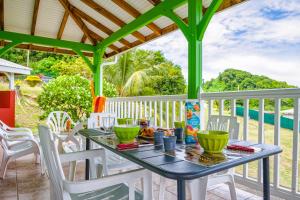 a table and chairs on the porch of a house at La Casita Verte vue sur mer & jardin tropical in Le Robert