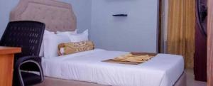 a bedroom with a white bed and a chair at BENJY palace hôtel in Matadi +2 photos