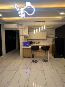 eine Küche mit Marmorboden und 2 Barhockern in der Unterkunft Modern 2BHK ApartmentPool Netflix in Rawalpindi