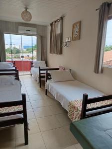 ein Hotelzimmer mit drei Betten und Balkon in der Unterkunft Pousada São João Batista in Cachoeira Paulista