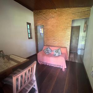ein Schlafzimmer mit einem rosa Bett und einer Backsteinwand in der Unterkunft Chalé da Mata in Cachoeiras de Macacu