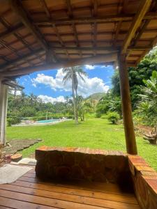 Eine Bank auf einer Veranda mit einer Palme im Hintergrund in der Unterkunft Chalé da Mata in Cachoeiras de Macacu