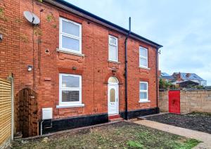 a brick house with a red door and a fence at Cosy Corner in Derby