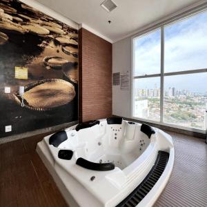 una vasca da bagno in una stanza con una grande finestra di Metropolitan Barcelona próximo ao Flamboyant e Autódromo Ar condicionado no quarto e na sala Piscina e jacuzzi no terraço academia completa restaurantes no térreo vaga privativa a Goiânia