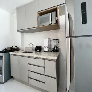 una cucina con mobili bianchi e un frigorifero in acciaio inossidabile di Metropolitan Barcelona próximo ao Flamboyant e Autódromo Ar condicionado no quarto e na sala Piscina e jacuzzi no terraço academia completa restaurantes no térreo vaga privativa a Goiânia