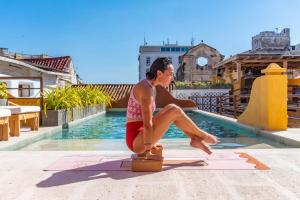a man sitting on a suitcase next to a swimming pool at Casa Carolina Luxury Wellness Hotel in Cartagena de Indias